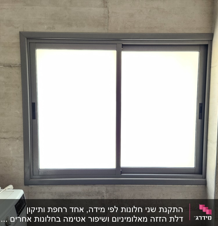 חלון אלומיניום עם מסגרת אפורה על קיר בטון